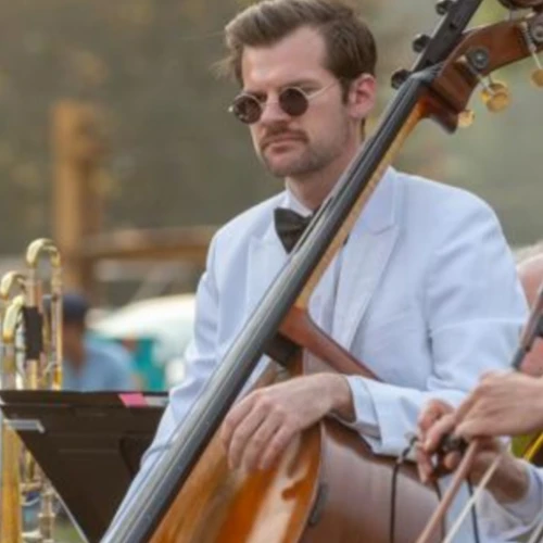 Musicians in white jackets are playing string instruments outdoors, possibly a formal event or concert setting.