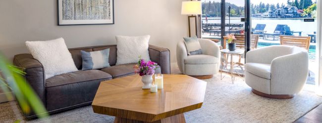 A bright, modern living room with a beige sofa, wooden coffee table, and a balcony view filled with natural light.