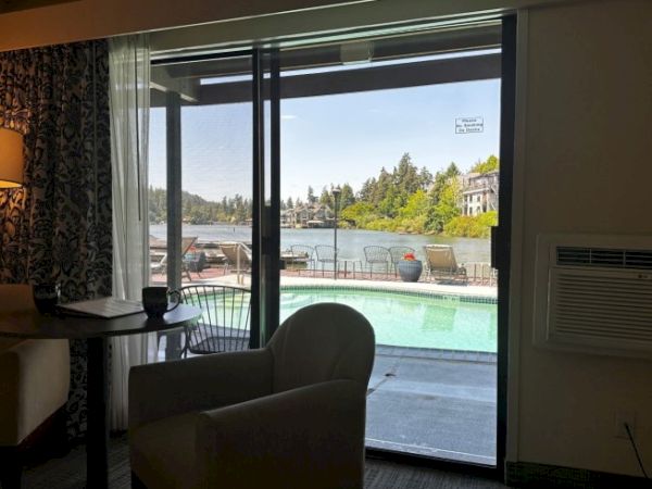 The image shows a room with a view of a pool and a lake beyond, seen through sliding glass doors.