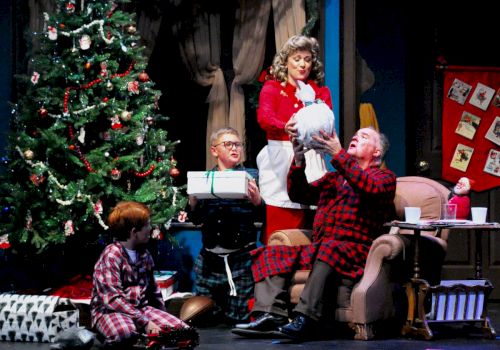 A festive Christmas scene with a decorated tree, people in pajamas, and a woman gifting an object, surrounded by presents and holiday decorations.