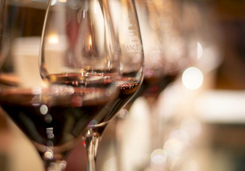Wine glasses on a bar, close-up with warm ambient lights in the background, blurred bottles and reflections.