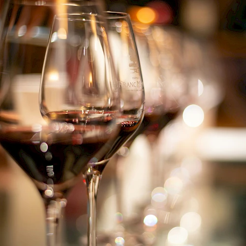 Wine glasses on a bar, close-up with warm ambient lights in the background, blurred bottles and reflections.